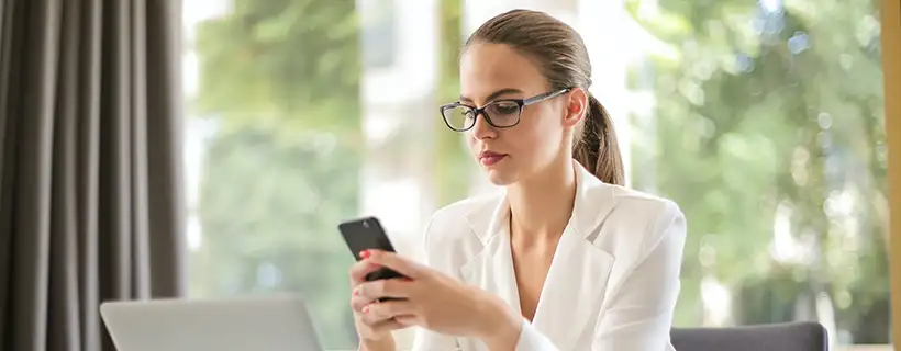 a woman looking at her phone checking for job alerts