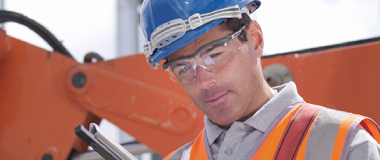 A construction worker with a big crane behind him