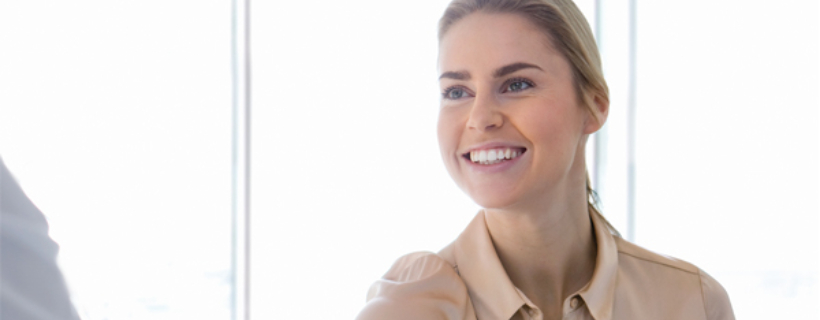 A woman shaking someone's hand and smiling