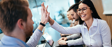 Two employees hi fiving each other after a successful meeting